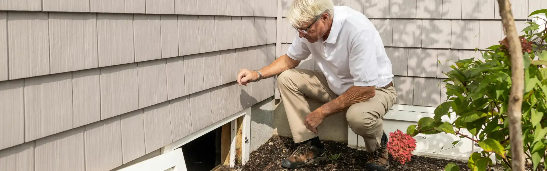 A Humboldt Termite & Pest Control technician opens a crawl space to check for pests during a routine pest prevention visit.